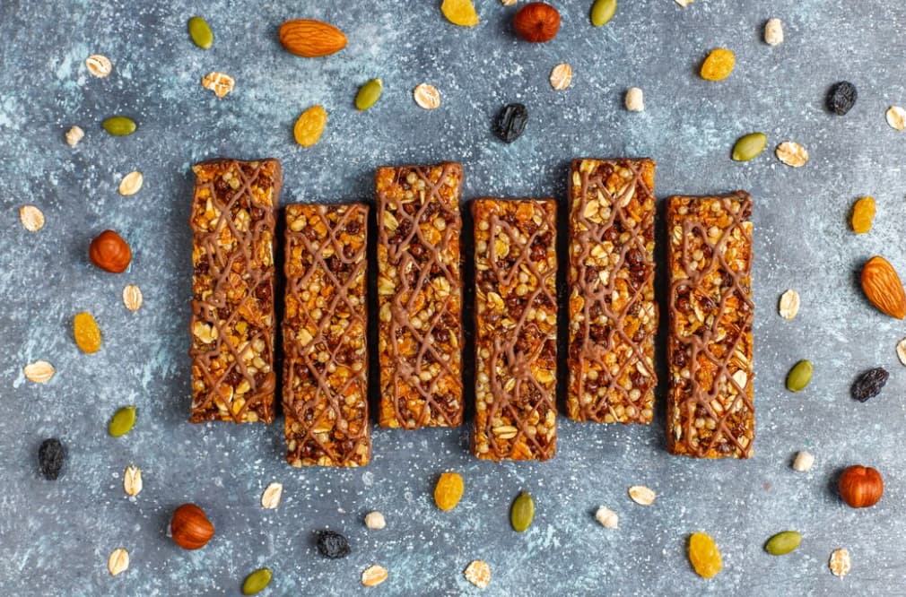 Nut and seed bars with chocolate drizzle on a grey backdrop